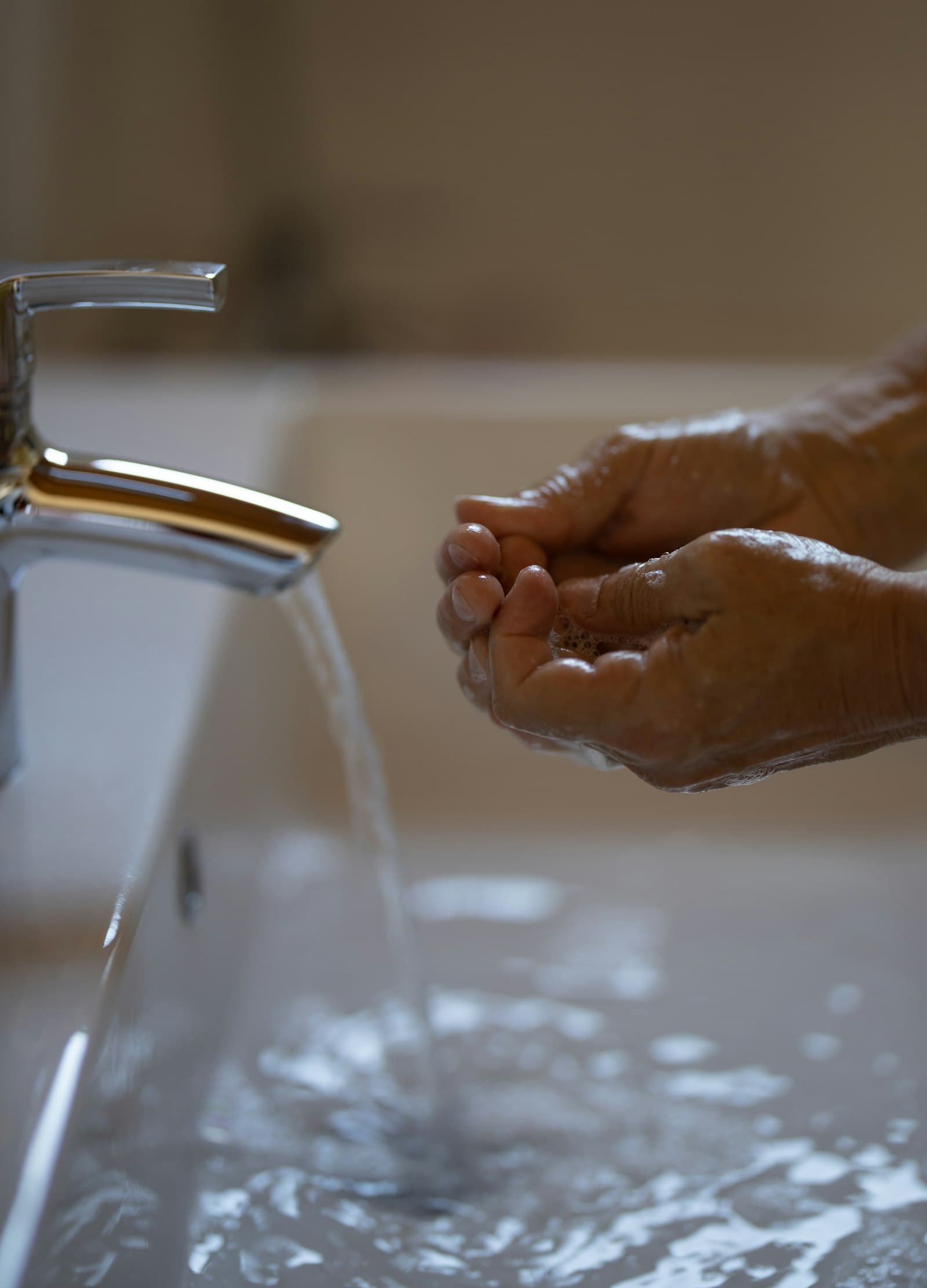 Hands under running water at a basin