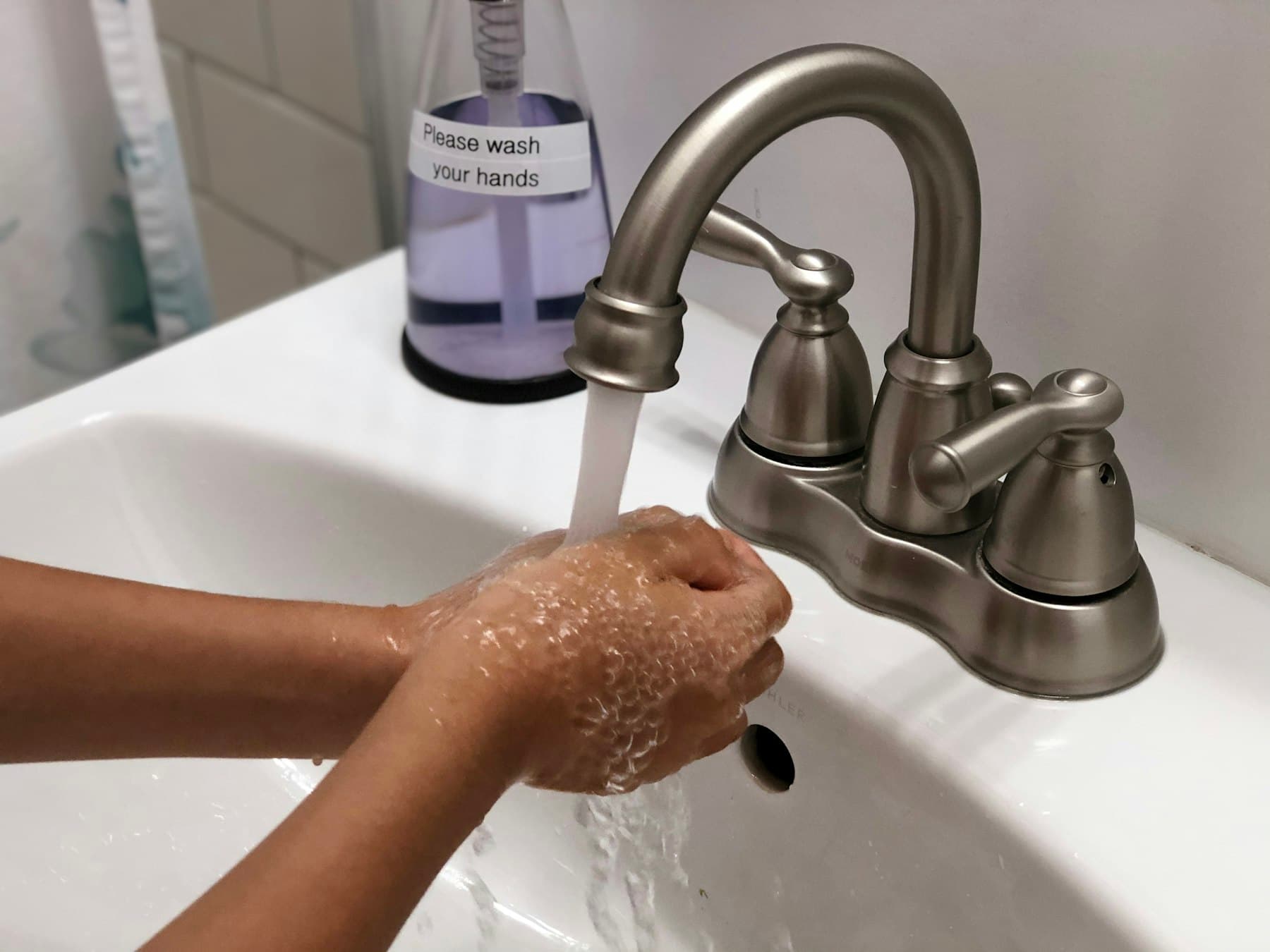A child washing their hands under a running tap